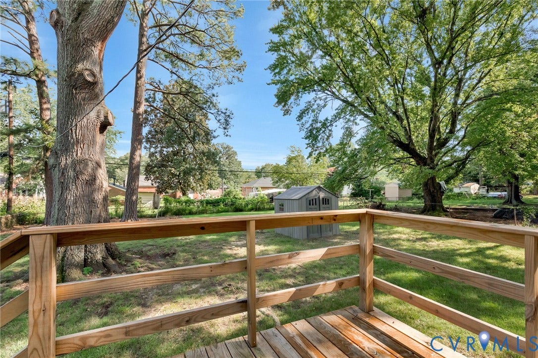 2807 Rothland Drive, Henrico, VA 23294 Wood deck with wood railing overlooking a grassy yard with mature trees and a storage shed