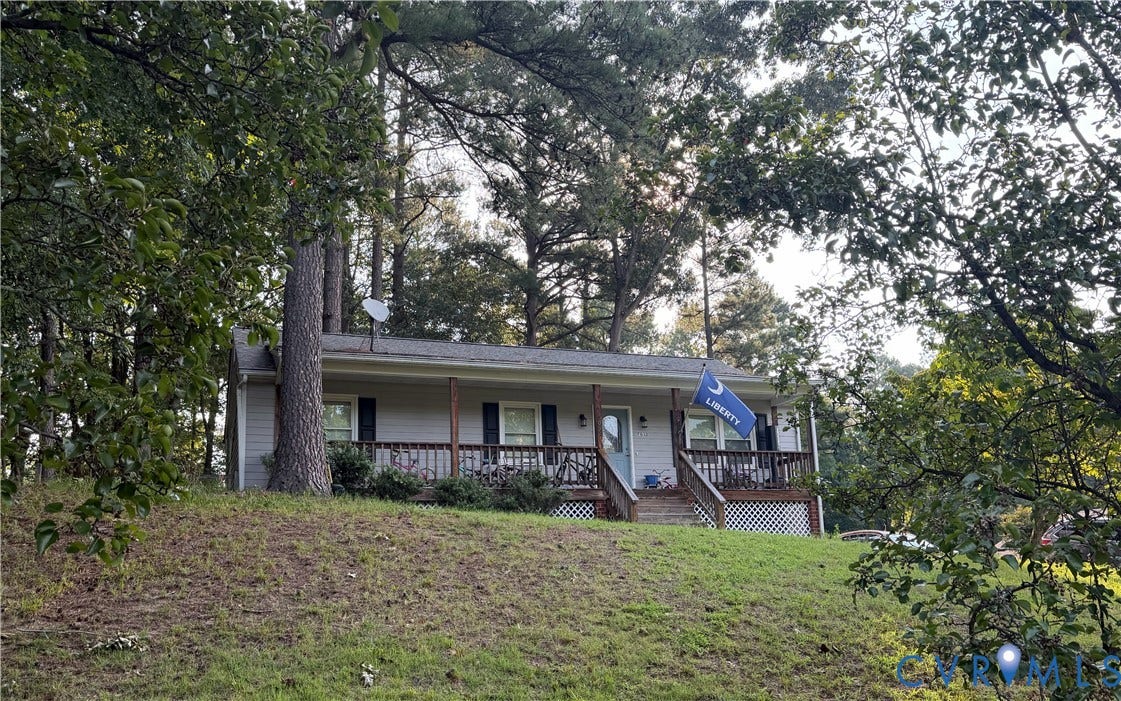 7032 Claybird Lane, Mechanicsville, VA 23111 Light-colored siding exterior, dark-toned shutters, covered front porch, wooden railings, and mature trees