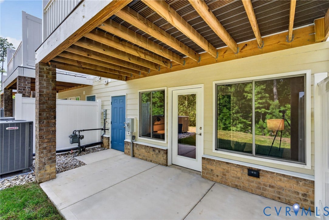 6537 Hardee Haven Place, Midlothian, VA 23112 Concrete patio with brick columns, private white fencing, an exterior door, and a large sliding window
