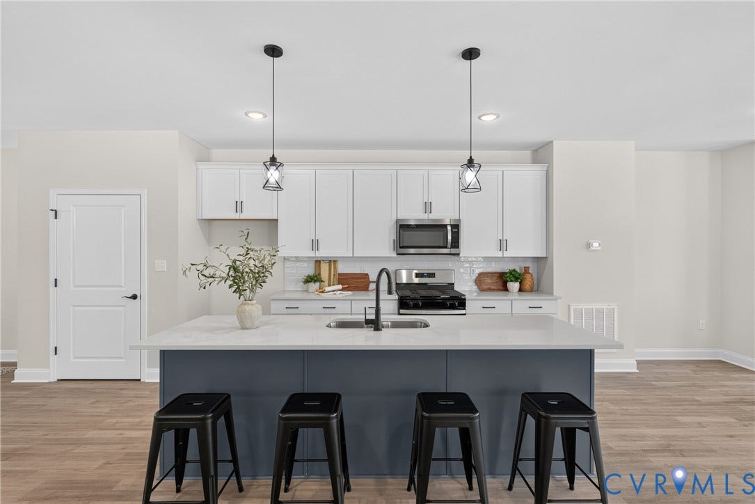 6537 Hardee Haven Place, Midlothian, VA 23112 Kitchen featuring a large island with seating, pendant lighting, stainless steel appliances, white cabinetry, and wood-finish flooring