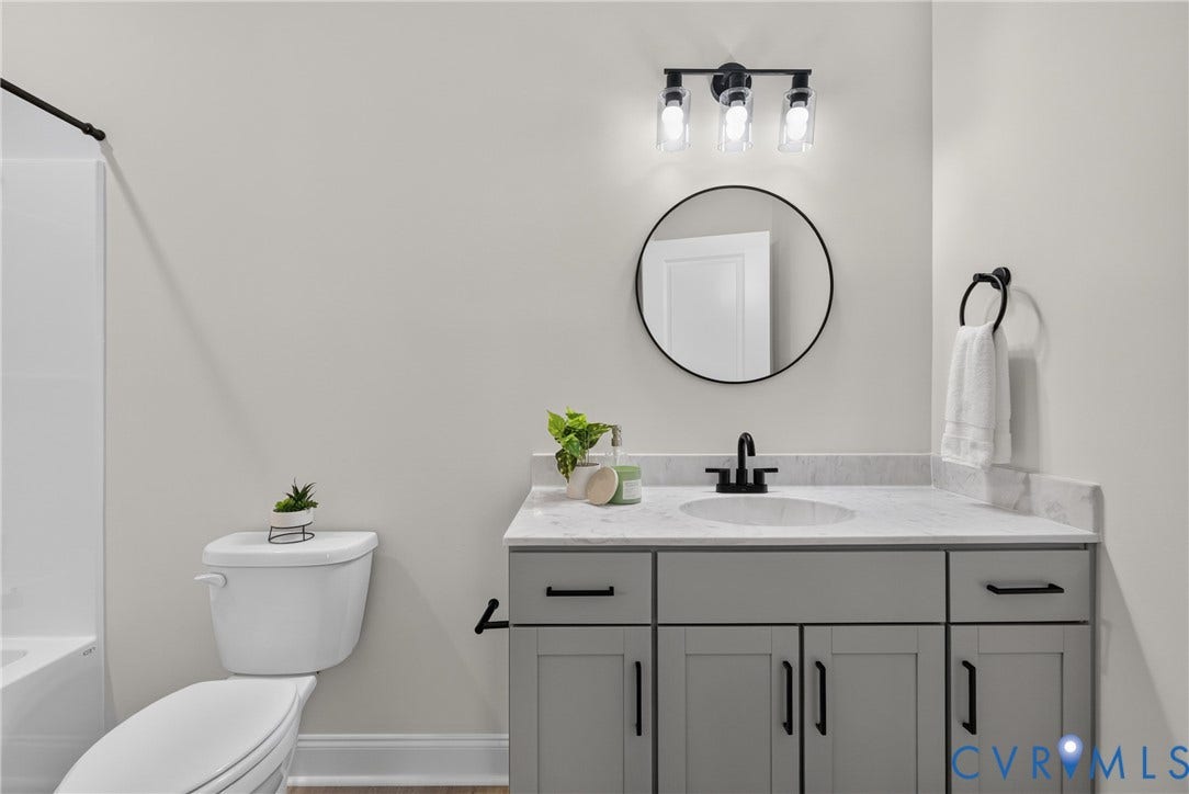6537 Hardee Haven Place, Midlothian, VA 23112 Vanity with a light gray finish and matte black hardware, white countertop, round mirror, and a three-light fixture