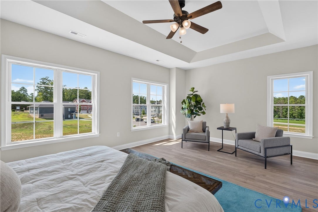 6537 Hardee Haven Place, Midlothian, VA 23112 Tray ceiling with a ceiling fan, multiple windows with white trim, light gray wall paint, and wood-finish flooring
