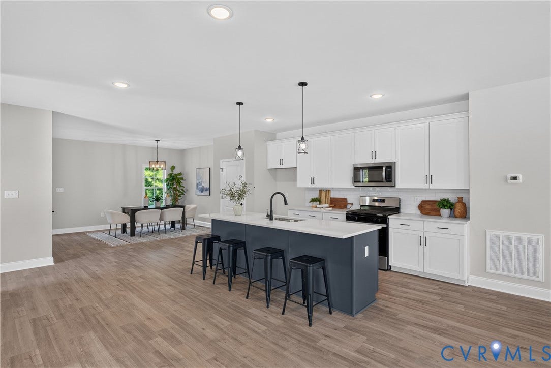 6537 Hardee Haven Place, Midlothian, VA 23112 Open-concept kitchen featuring white cabinetry, a dark-toned island with seating, stainless steel appliances, and wood-finish flooring throughout