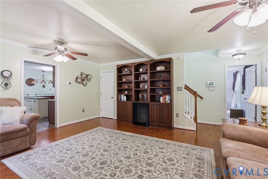 5295 Chimney Springs Drive, Saunders Acres, Goochland, VA 23063 Spacious primary suite featuring hardwood flooring, dual ceiling fans with integrated lighting, and built-in wooden cabinetry with shelving