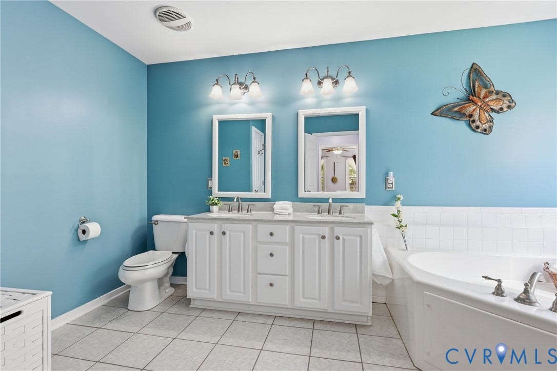 5295 Chimney Springs Drive, Saunders Acres, Goochland, VA 23063 Double vanity with white cabinetry and chrome hardware, featuring dual framed mirrors and wall-mounted light fixtures