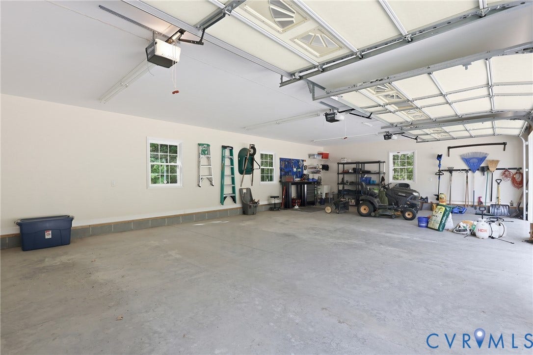 5295 Chimney Springs Drive, Saunders Acres, Goochland, VA 23063 Spacious garage featuring concrete flooring, multiple windows, and overhead garage door mechanisms