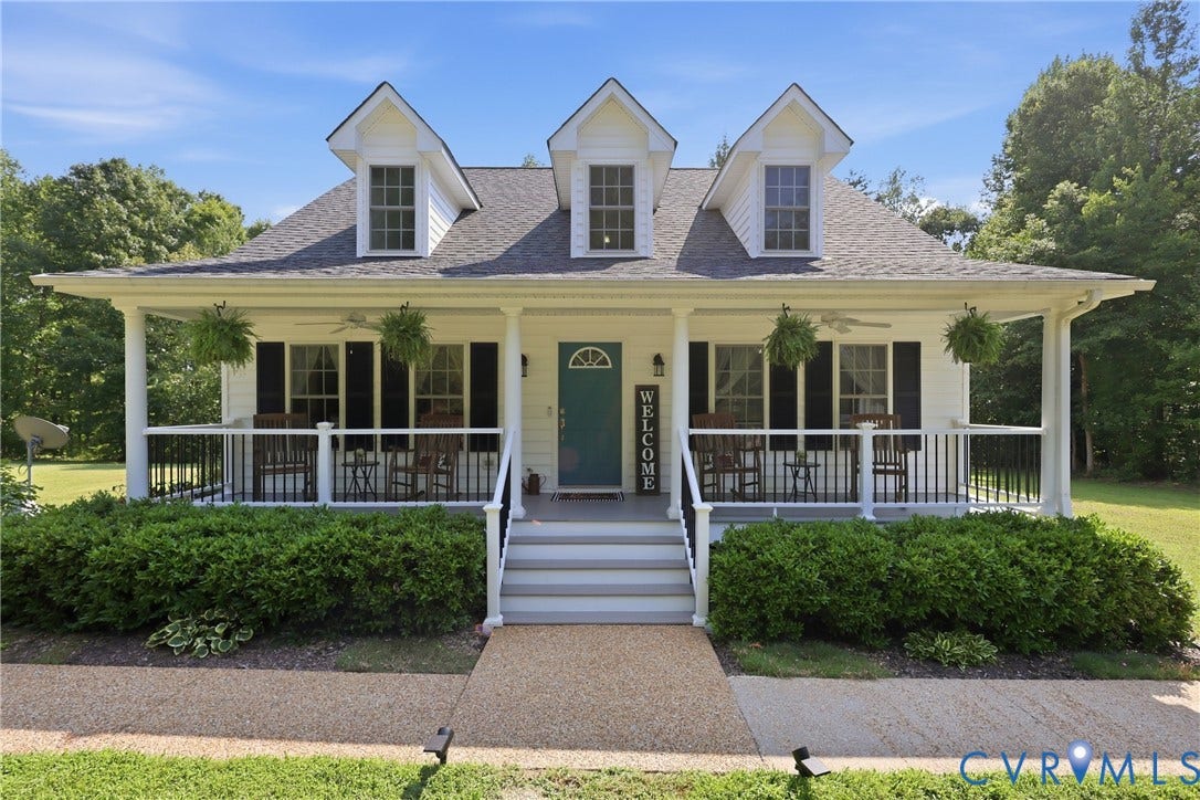 5295 Chimney Springs Drive, Saunders Acres, Goochland, VA 23063 Classic Colonial-style residence featuring a symmetrical facade with three front-facing dormers, cream exterior siding, and a welcoming covered front porch with white columns and railings