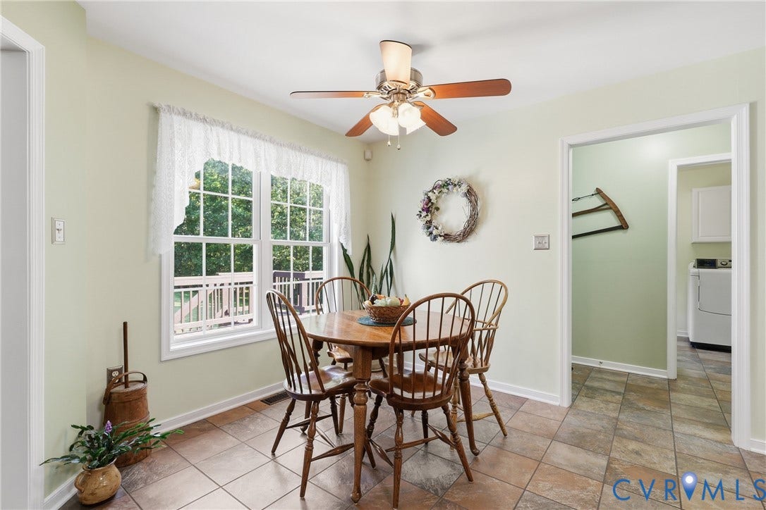 5295 Chimney Springs Drive, Saunders Acres, Goochland, VA 23063 Bright dining area featuring a ceiling fan with integrated lighting, large window overlooking a deck, and durable tile flooring