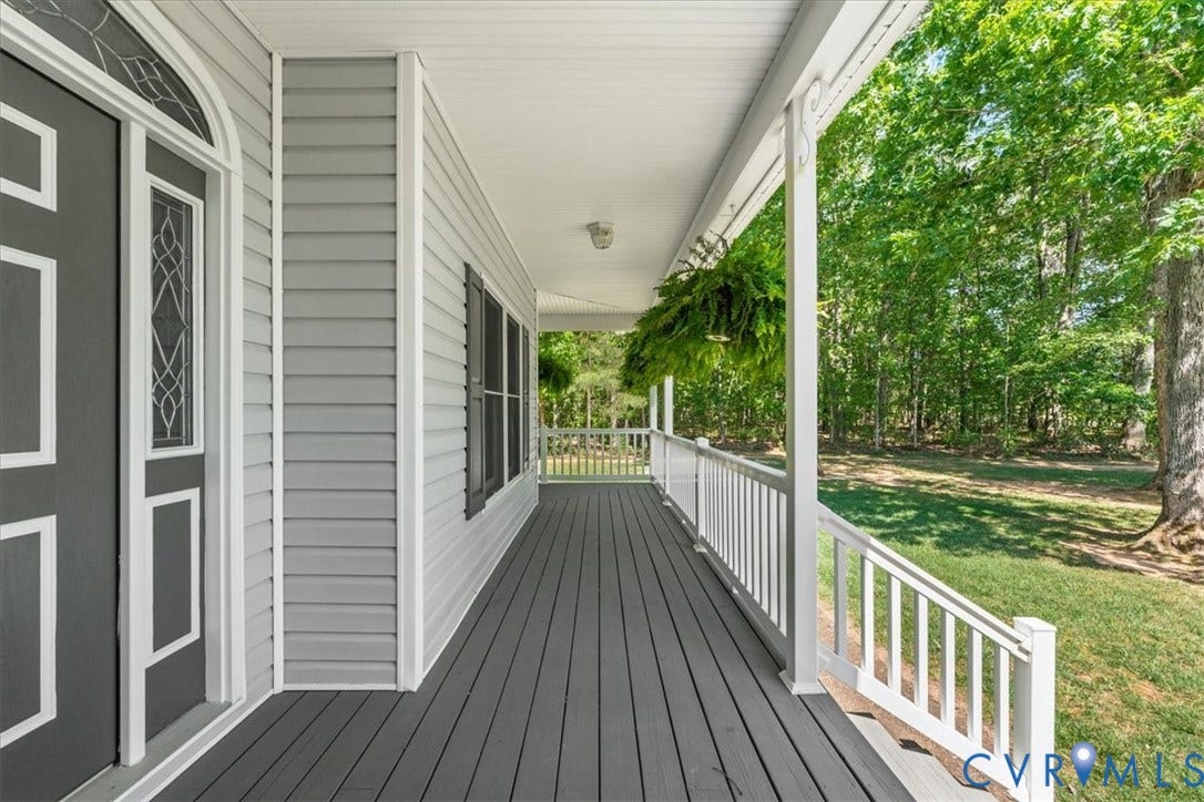 3060 Moyer Road, Powhatan, VA 23139 Expansive covered front porch with dark gray decking, white railing, light gray siding, and a decorative glass front door