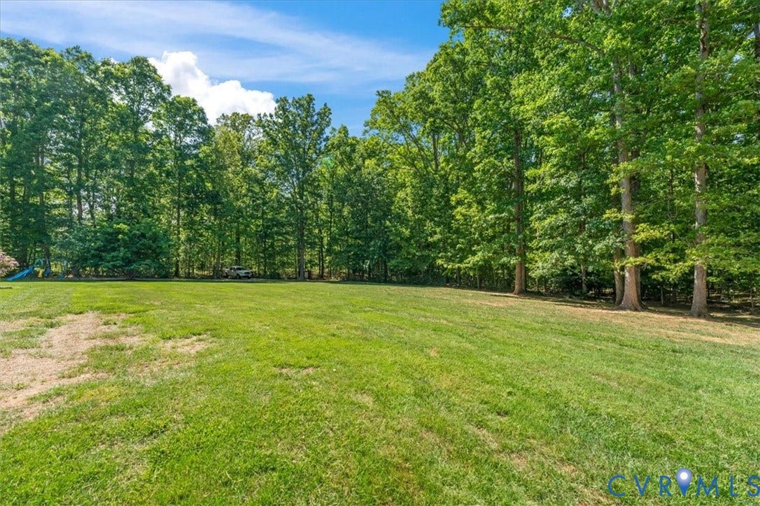 3060 Moyer Road, Powhatan, VA 23139 Expansive lawn with mature tree line bordering the property, offering generous outdoor space and natural privacy screening