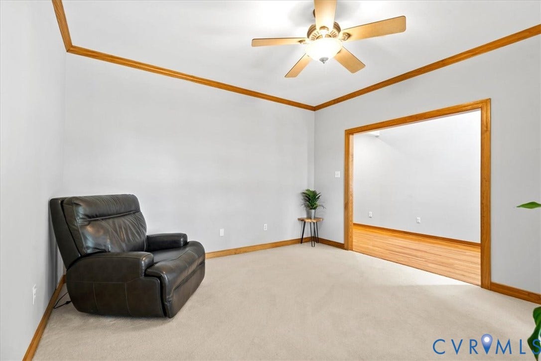 3060 Moyer Road, Powhatan, VA 23139 Carpet flooring, crown molding, wood-finish trim, ceiling fan light fixture, and a wide cased opening to an adjacent room with wood-finish flooring