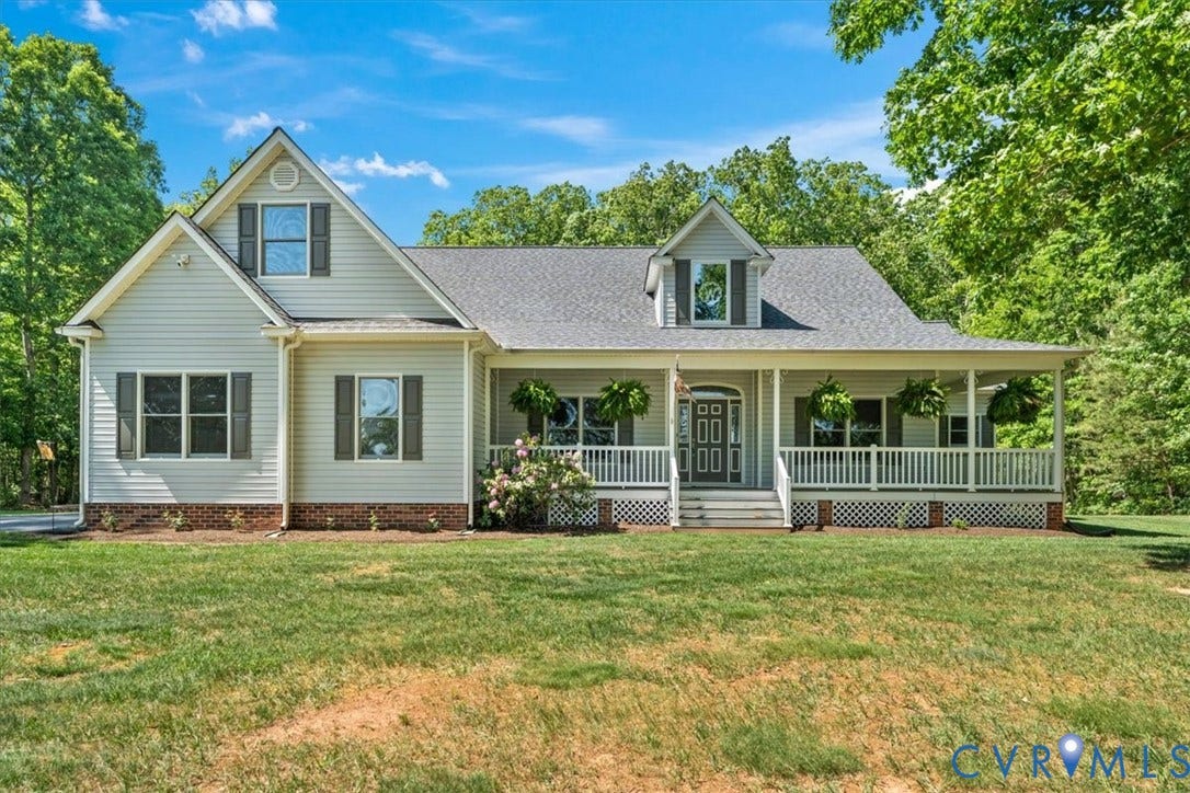 3060 Moyer Road, Powhatan, VA 23139 Classic farmhouse residence featuring a light-colored vinyl exterior, pitched roofline with architectural gable detailing, and a full-width front porch with white railings and columns