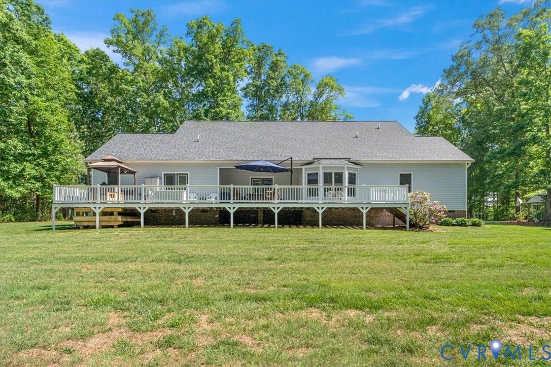 3060 Moyer Road, Powhatan, VA 23139 Spacious ranch-style home elevated on a full foundation with an expansive wraparound deck featuring white railings and support columns