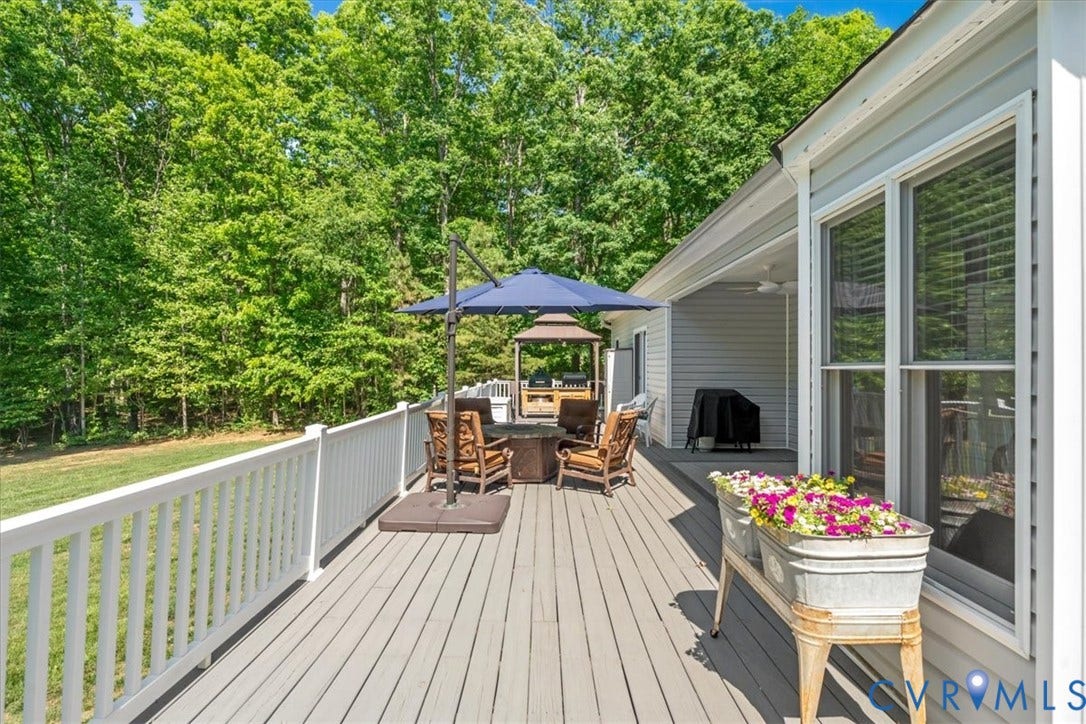 3060 Moyer Road, Powhatan, VA 23139 Expansive outdoor deck with white railing, light-toned decking, and an attached covered patio featuring a ceiling fan