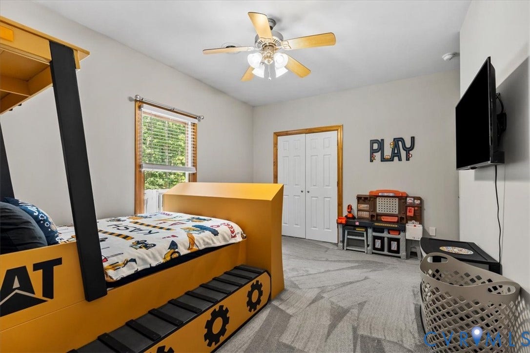 3060 Moyer Road, Powhatan, VA 23139 Ceiling fan with light fixture, window with blinds, bi-fold closet doors with wood trim, wall-mounted television, and patterned carpeting