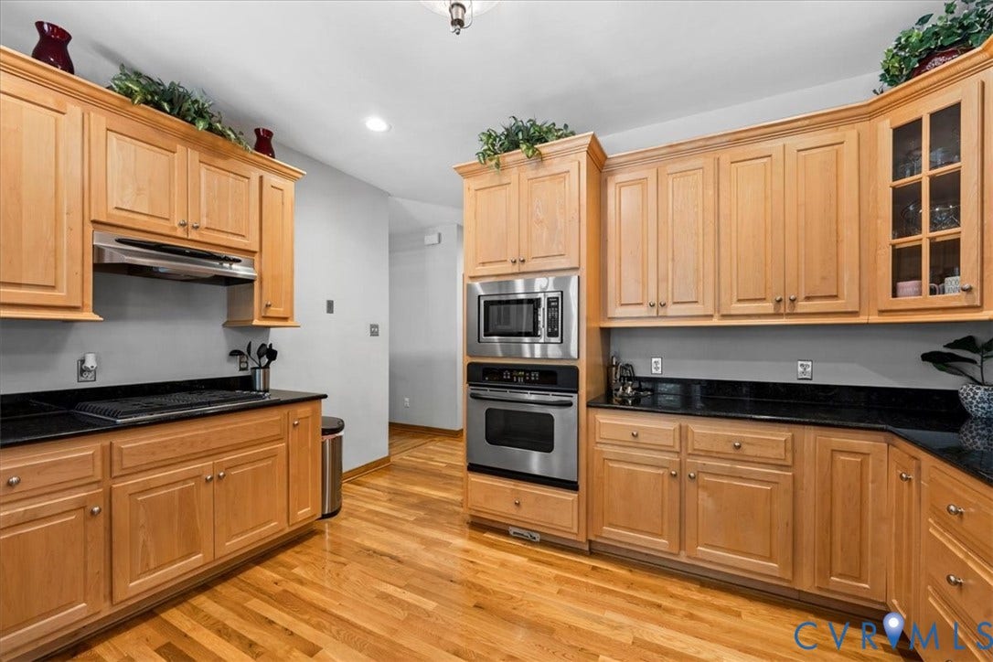 3060 Moyer Road, Powhatan, VA 23139 Hardwood flooring, stainless steel appliances, built-in microwave, dark countertops, and light wood cabinetry
