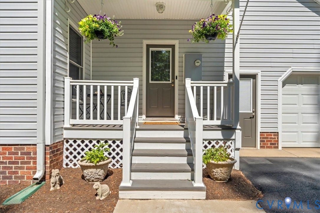 3060 Moyer Road, Powhatan, VA 23139 Welcoming front entry featuring a gray horizontal-plank siding exterior with white composite railings and balusters, brick foundation accents, and a centered entry door flanked by symmetrical planter boxes