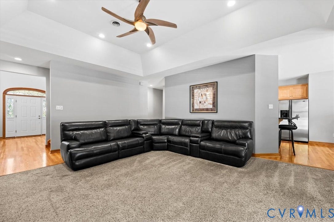3060 Moyer Road, Powhatan, VA 23139 Spacious recreation room featuring a sectional leather seating arrangement, warm wood-finish flooring, neutral carpeting, recessed ceiling lighting, and a ceiling fan with brass accents