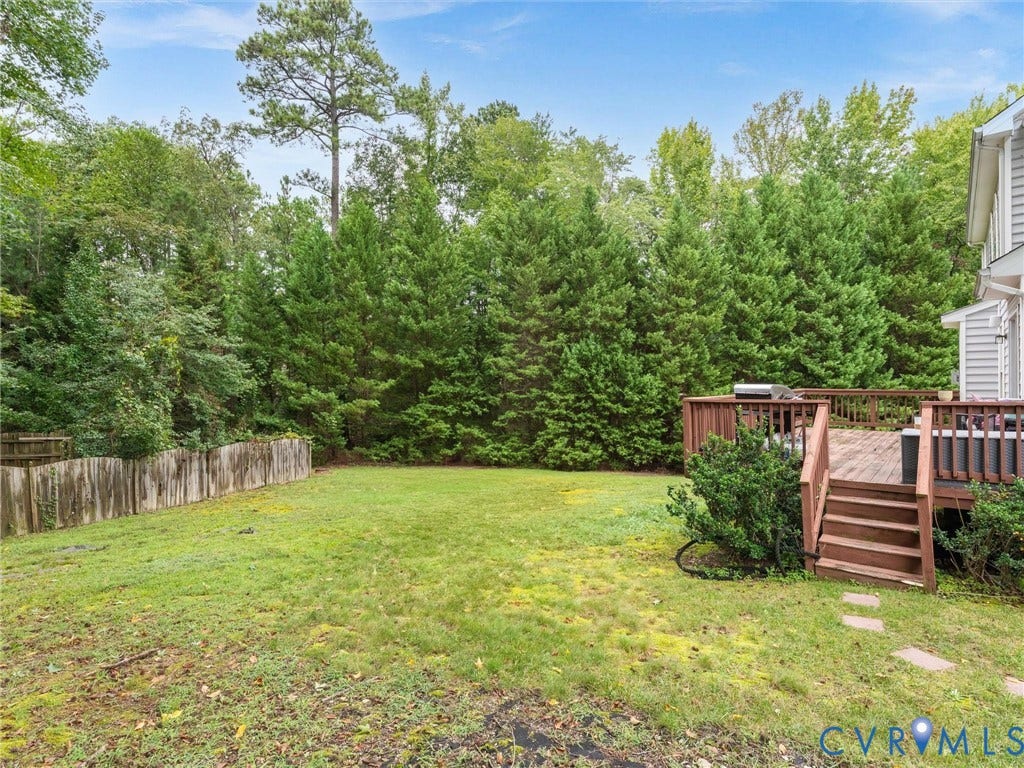 5017 Sadler Glen Place, Glen Allen, VA 23060 Expansive back lawn area with a wooden privacy fence, mature trees, and a multi-level wood deck with stairs