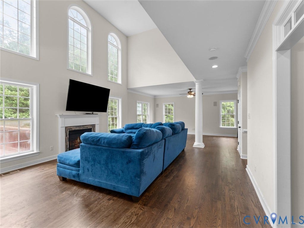 5017 Sadler Glen Place, Glen Allen, VA 23060 Two-story living area featuring dark wood-finish flooring, a fireplace with a white mantel, and arched transom windows