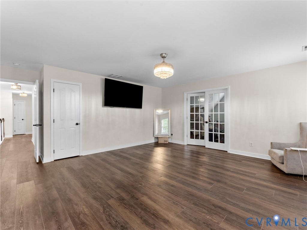 5017 Sadler Glen Place, Glen Allen, VA 23060 Spacious room featuring wood-finish flooring, white walls, and a decorative ceiling light fixture