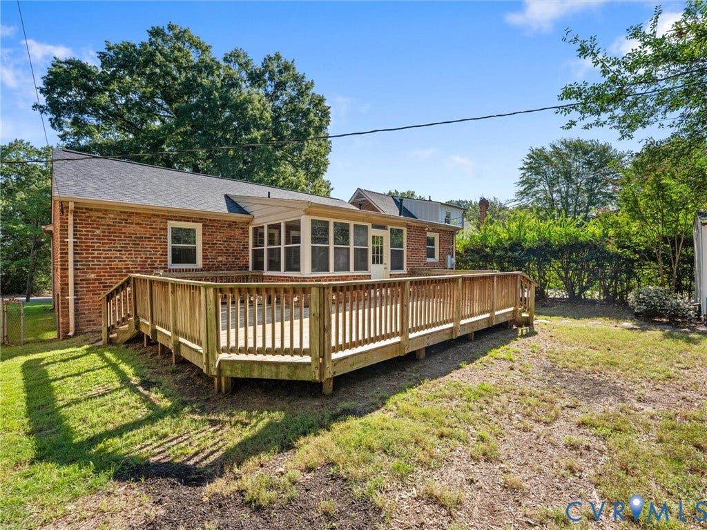 Brick exterior with a large wood deck featuring a built-in ramp and railings