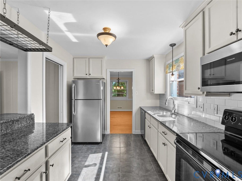 Kitchen featuring granite-style countertops, stainless steel appliances, subway tile backsplash, white cabinetry, and tile flooring