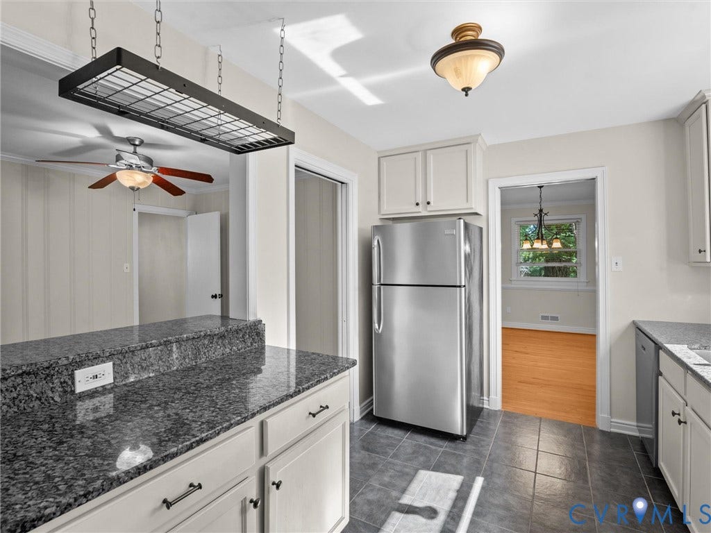 Kitchen featuring gray tiled flooring, light-toned cabinetry, and dark granite countertops