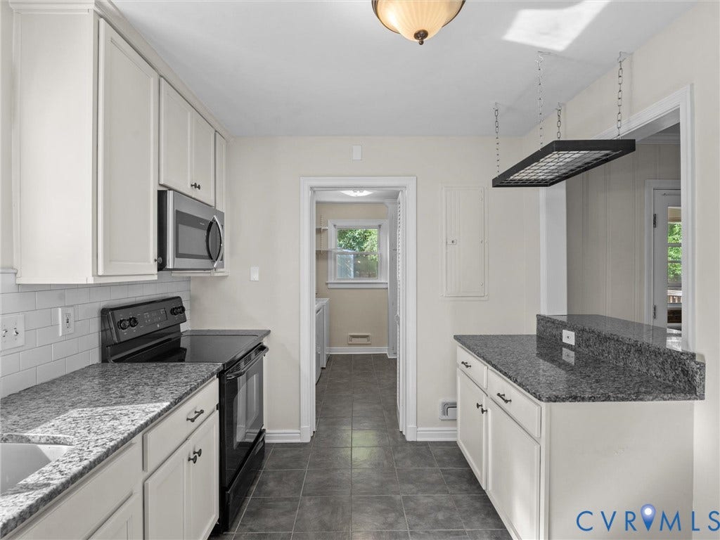 Kitchen featuring white shaker-style cabinetry, dark granite countertops, stainless steel appliances, a white subway tile backsplash, and dark tile flooring