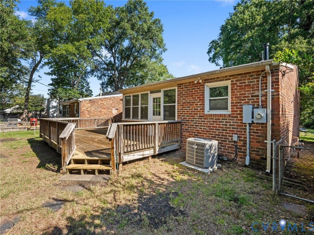 Brick exterior featuring a wood deck with railings and steps
