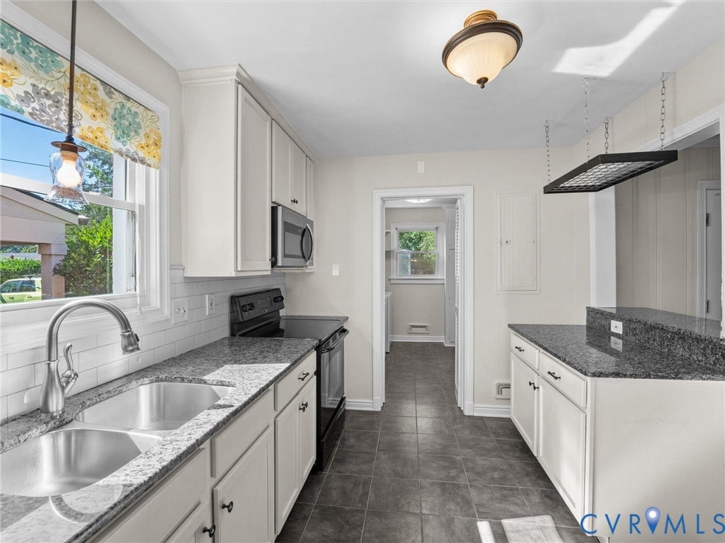 White cabinetry, granite-finish countertops, stainless steel double-basin sink, built-in microwave, and tile flooring