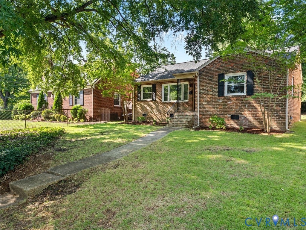 Brick exterior with black shutters and a covered entry, featuring a front lawn and paved walkway