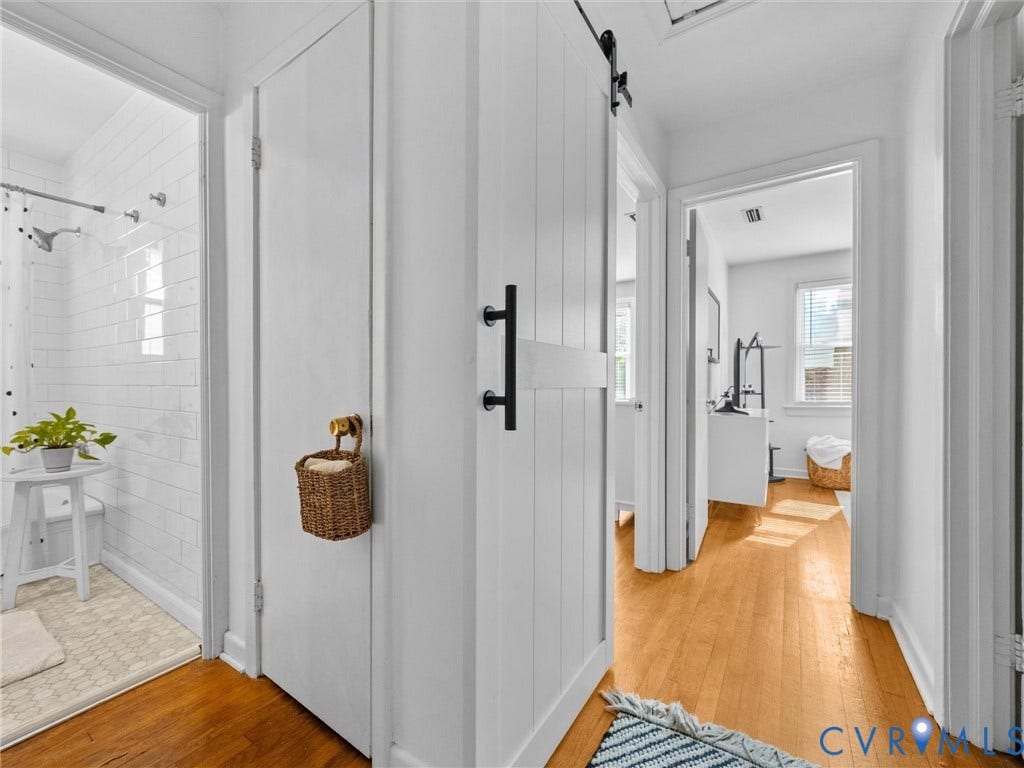 2328 Leah Road, Richmond, VA 23230 Wood-finish flooring, white shiplap barn door with black hardware, white subway tile shower surround, white hex tile shower floor, white interior doors