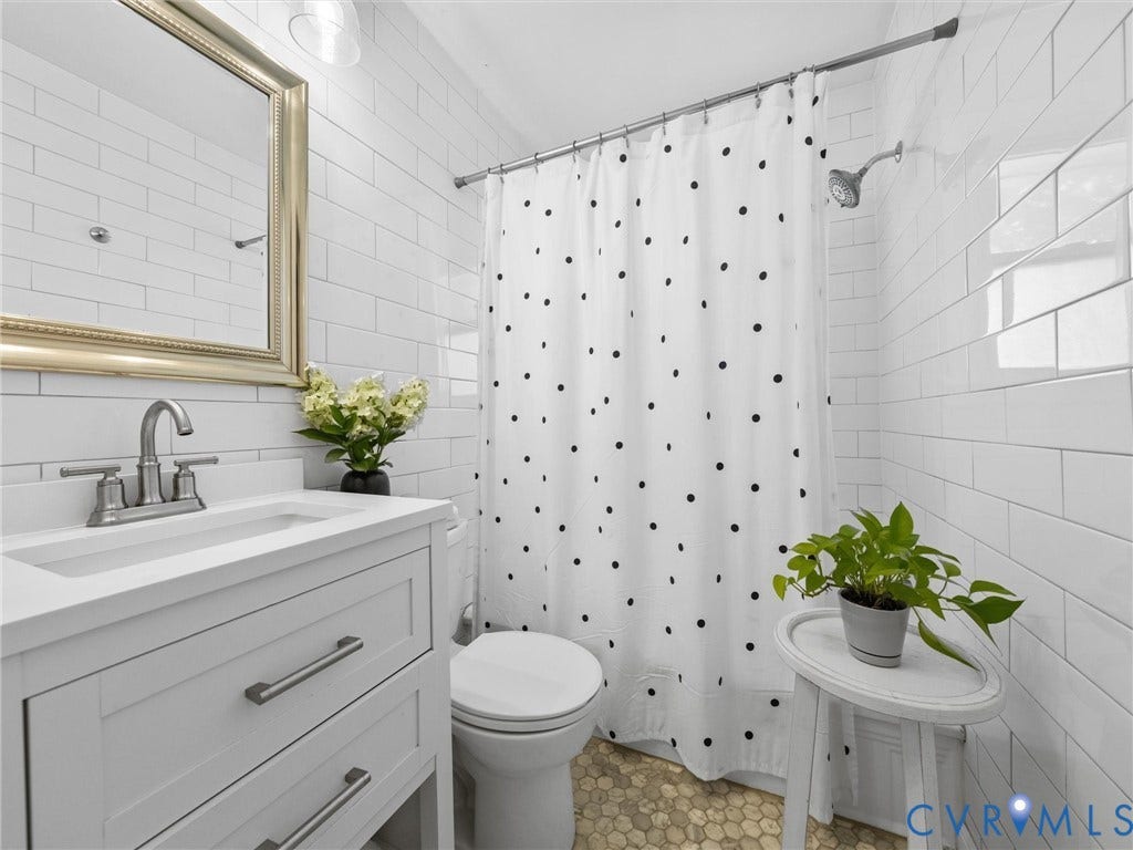 2328 Leah Road, Richmond, VA 23230 White subway tile walls, a white vanity with brushed nickel hardware, and a gold-framed mirror