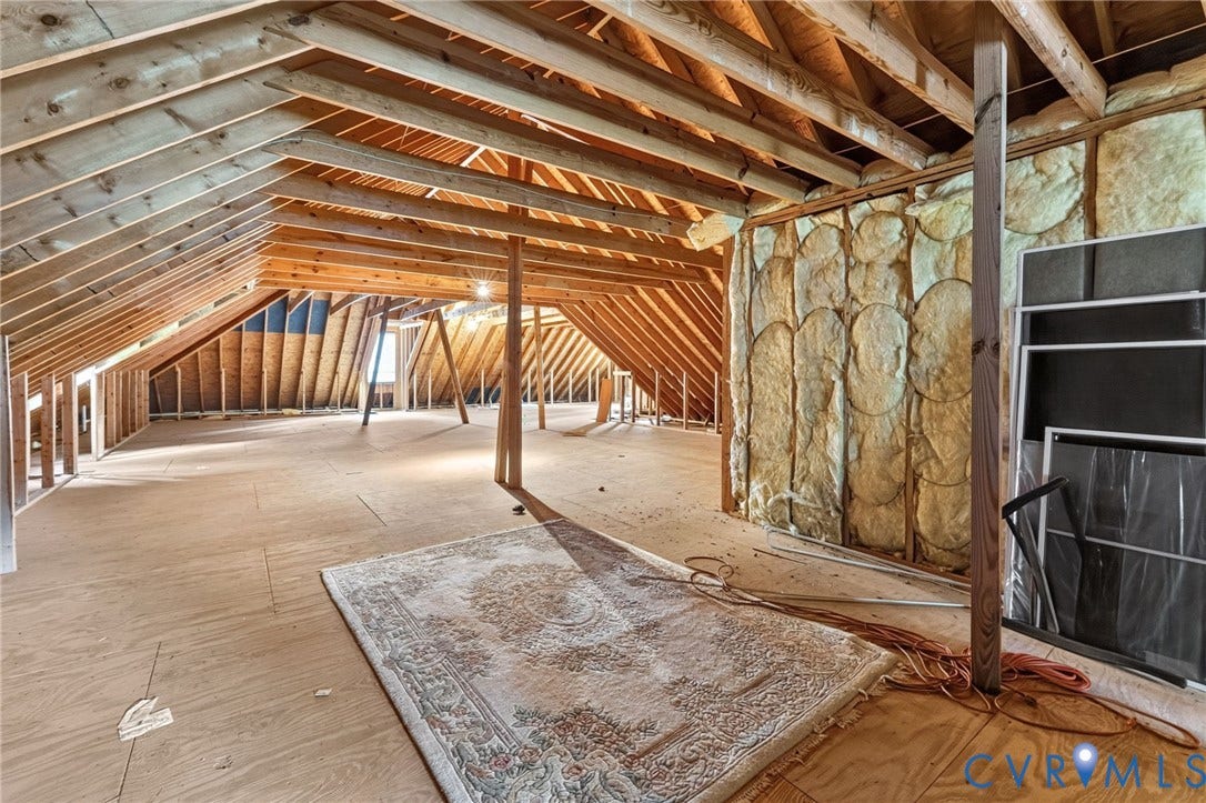Spacious unfinished attic with exposed wooden beam framing and vaulted ceiling structure