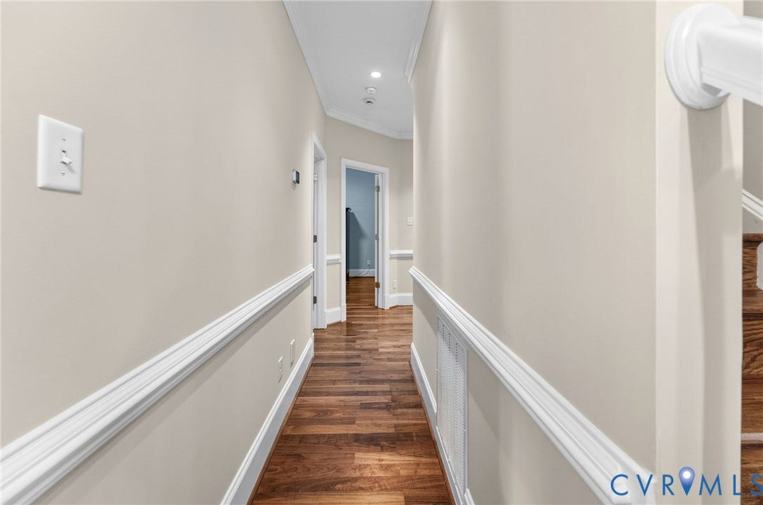 Wood-finish flooring, neutral wall tones, decorative chair rail molding, recessed ceiling lighting, and crisp white trim
