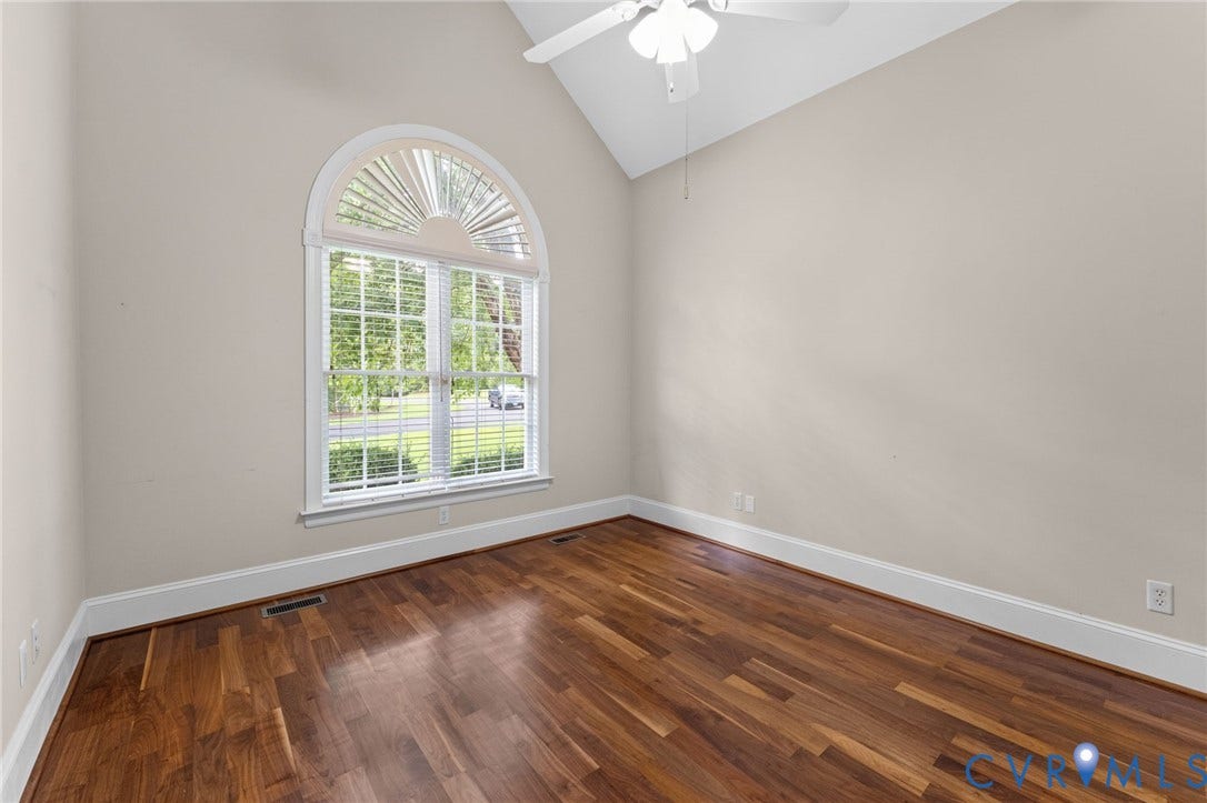 Vaulted ceiling with a ceiling fan, hardwood flooring, and an arched window with blinds