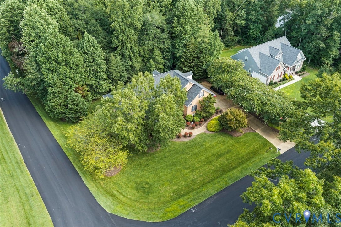 Residence featuring a brick exterior, multiple gables, and a mature treed setting