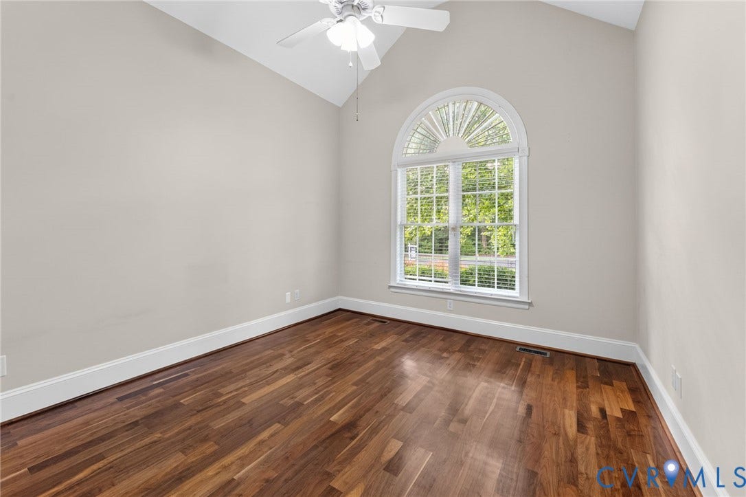 Vaulted ceiling with a ceiling fan, hardwood flooring, and an arched window