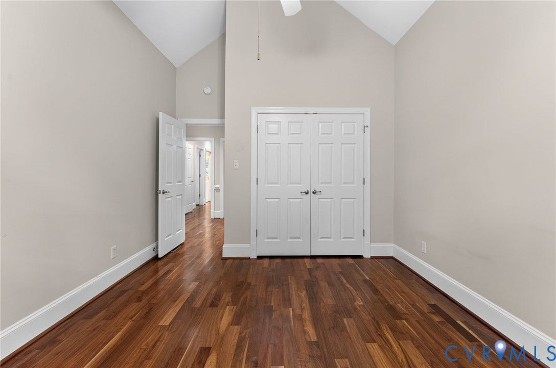 Vaulted ceilings, wood-finish flooring, paneled doors, and neutral wall tones