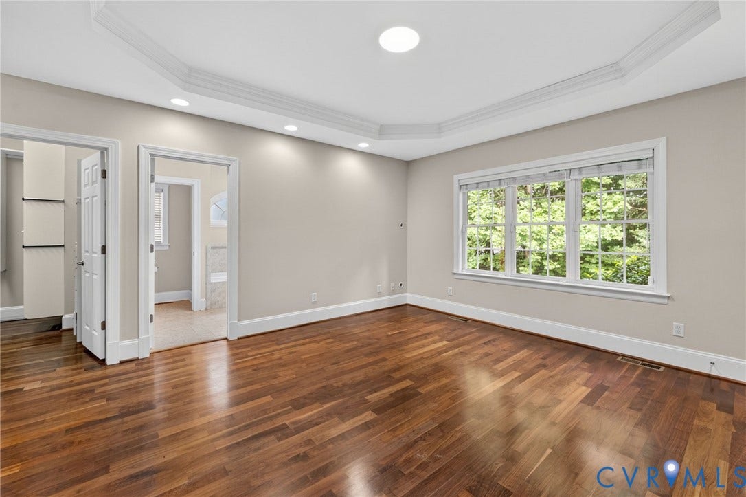Bright, light-filled room showcasing rich wood-finish flooring, recessed ceiling lighting, and abundant natural light from triple-pane windows
