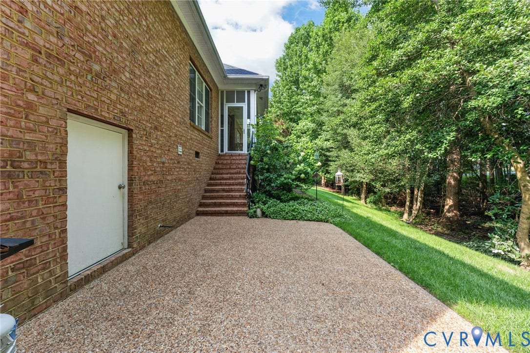 Brick exterior with an exposed aggregate patio, brick stairs, and a screened-in porch