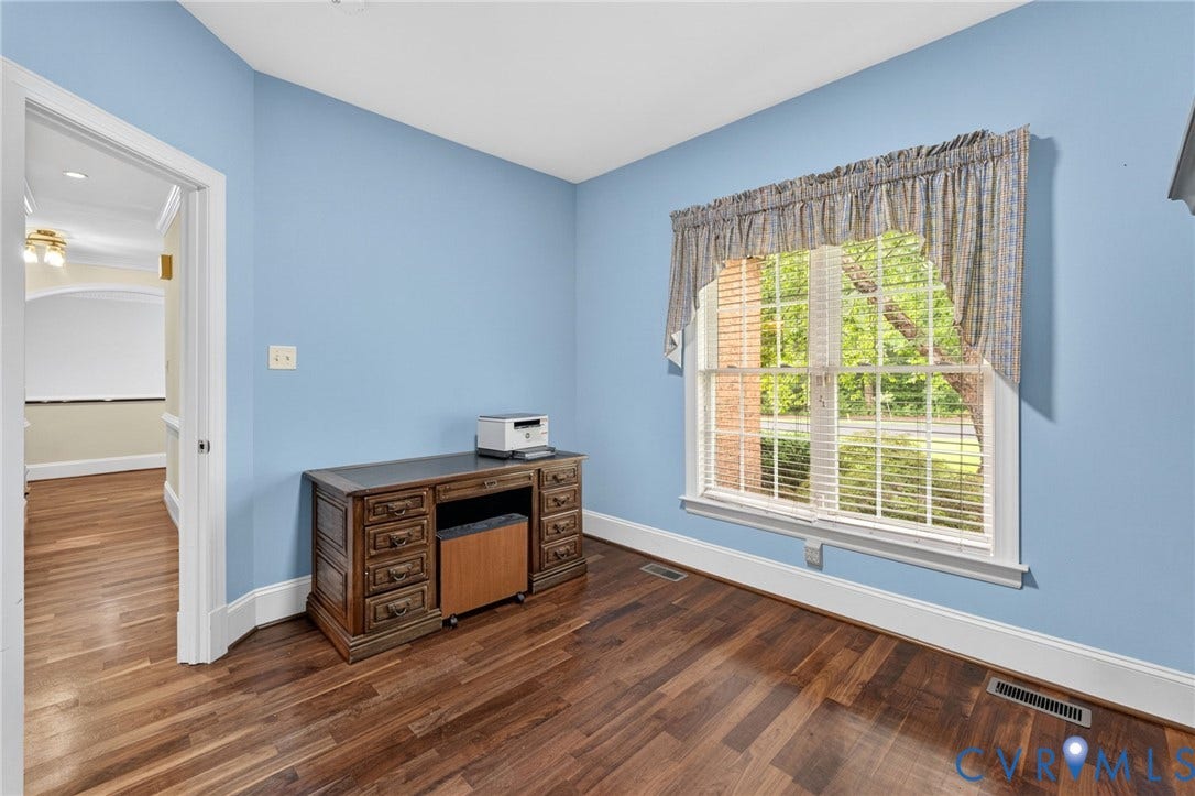 Hardwood flooring, painted walls, window with blinds, white trim, and a doorway