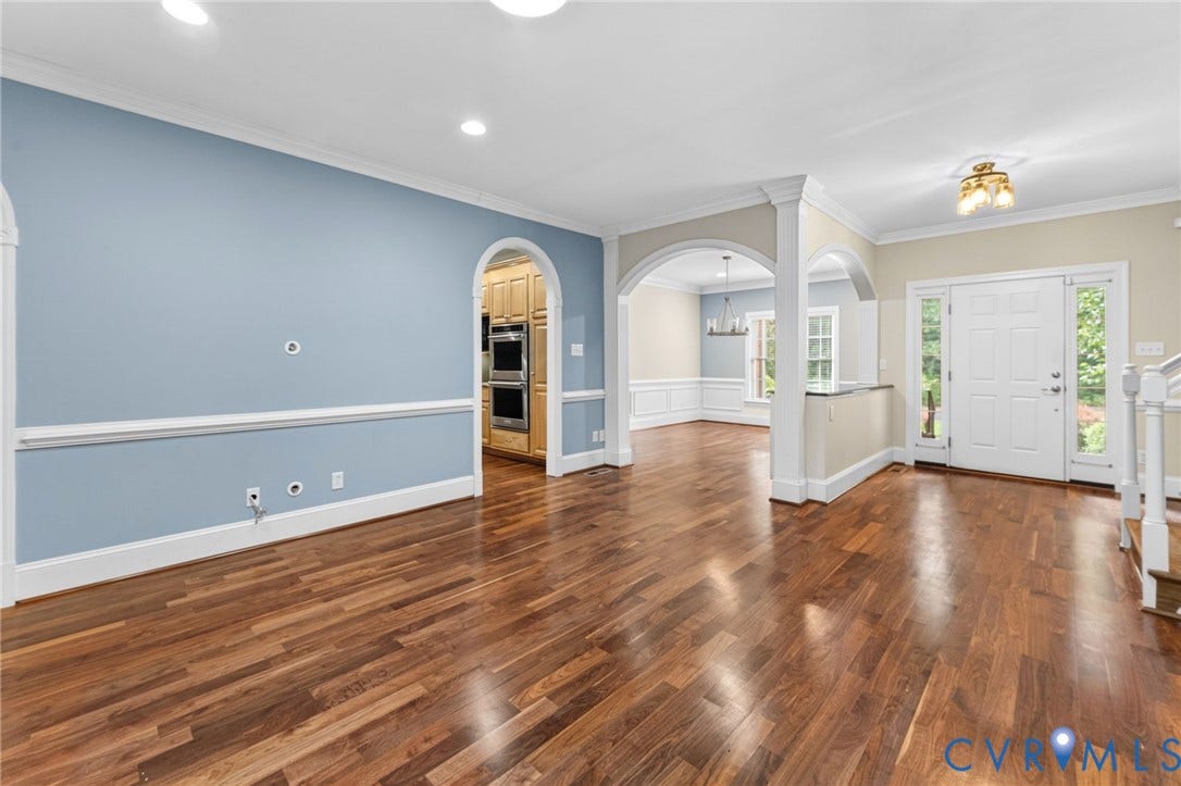 Hardwood flooring throughout, arched doorways, crown molding, double-oven built-in, and a paneled front door with sidelights