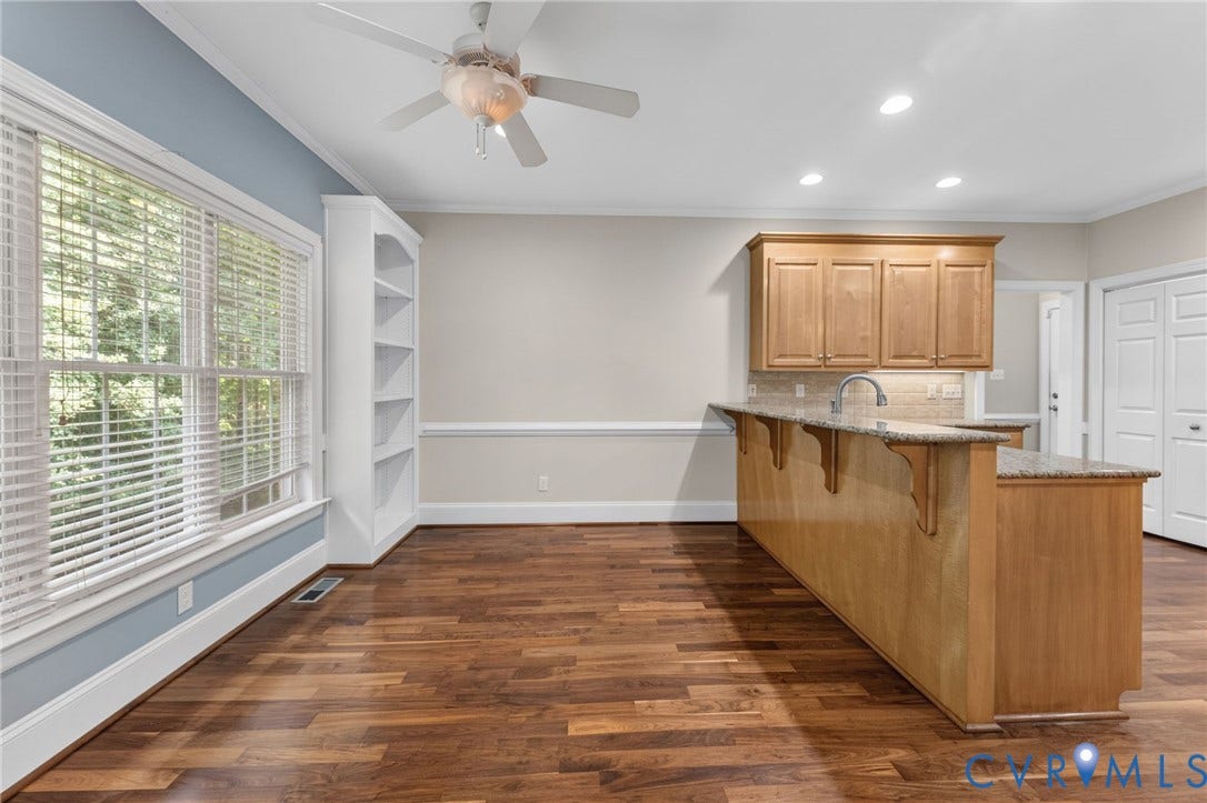 Wood-finish flooring, built-in shelving, expansive windows, kitchen island with granite countertop, and recessed lighting