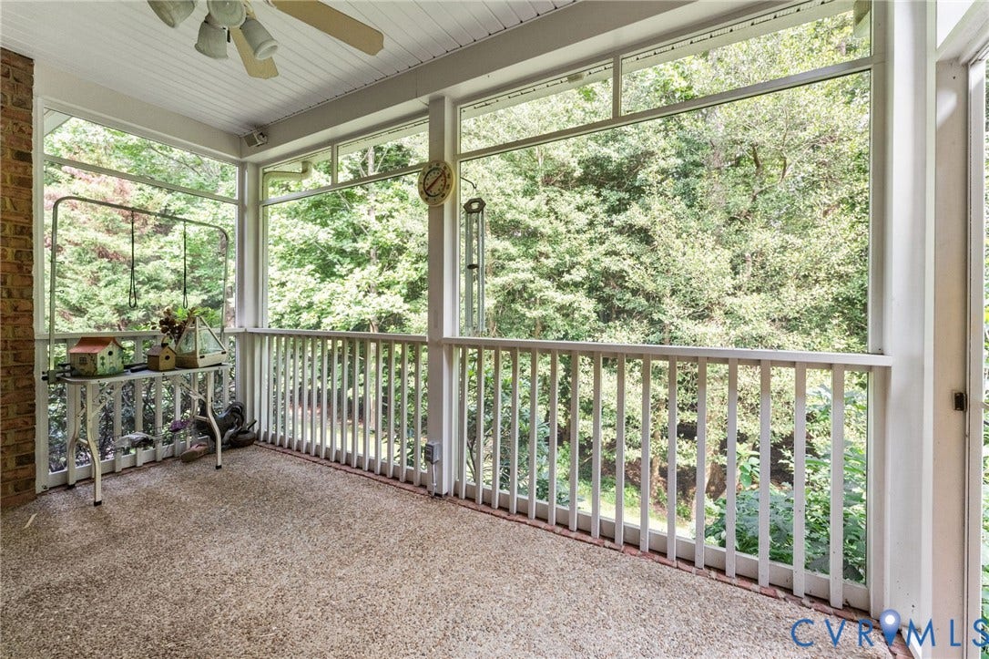 Screened porch with brick column, textured flooring, and a ceiling fan