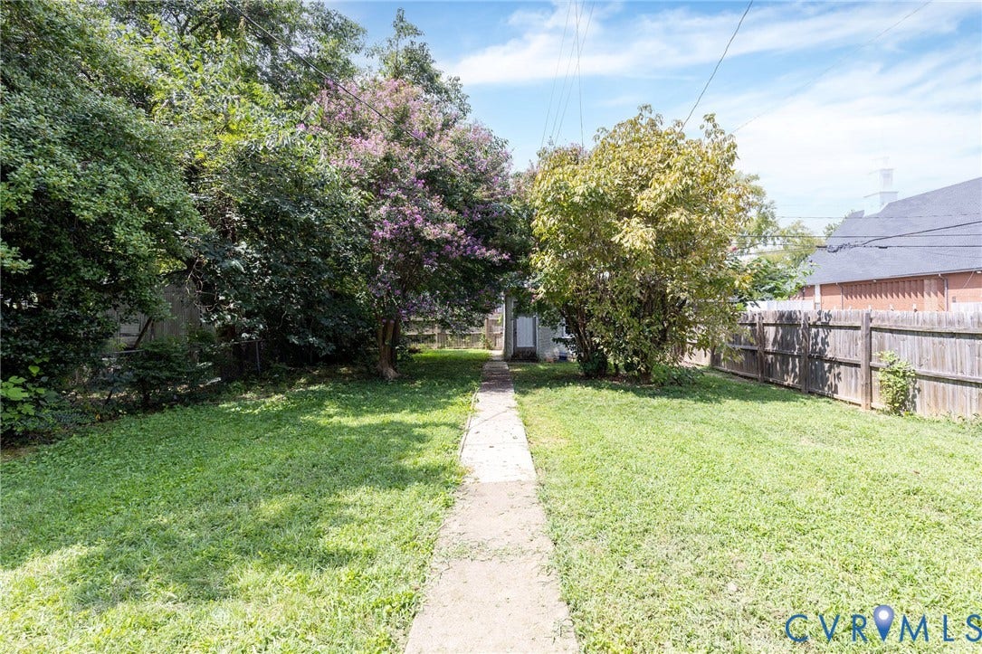 2726 Hanes Avenue, Brookland Park, Richmond, VA 23222 Expansive grass yard with a concrete pathway leading to the rear of the property, featuring a wood fence and mature trees