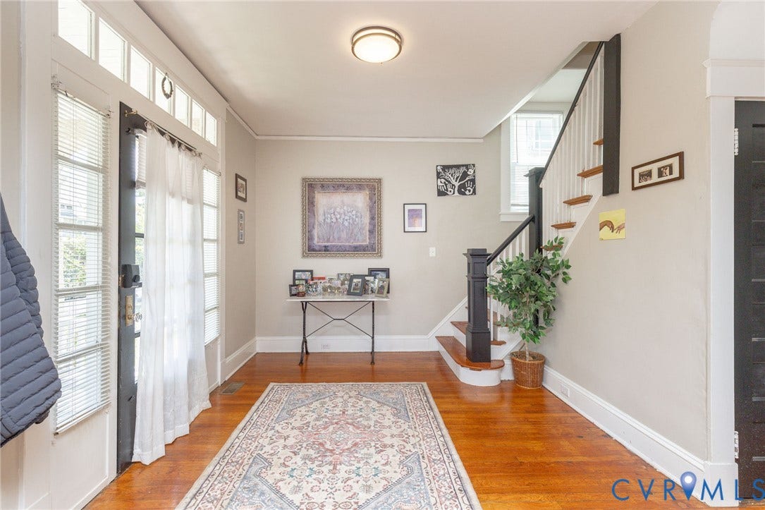 2726 Hanes Avenue, Brookland Park, Richmond, VA 23222 Hardwood flooring throughout, a staircase with dark newel posts and handrails, white trim, and a glass-paneled entry door with transom windows