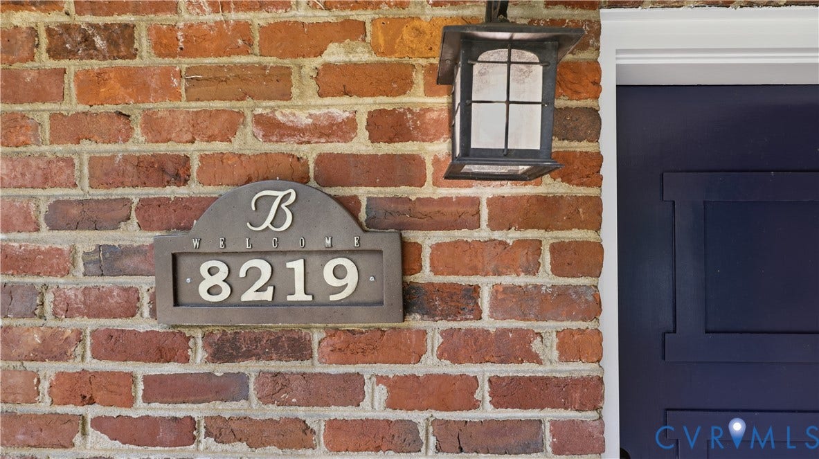 Brick exterior with a wall-mounted outdoor lantern and a decorative address plaque