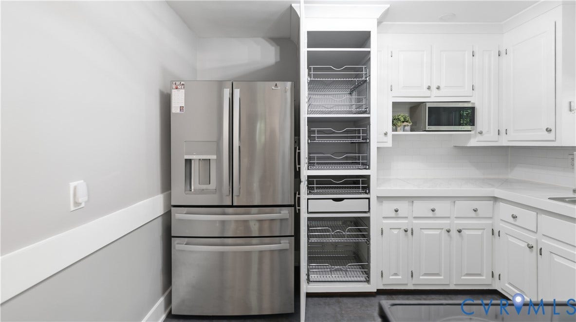 White cabinetry with silver hardware, integrated microwave shelf, white countertops, and a subway tile backsplash
